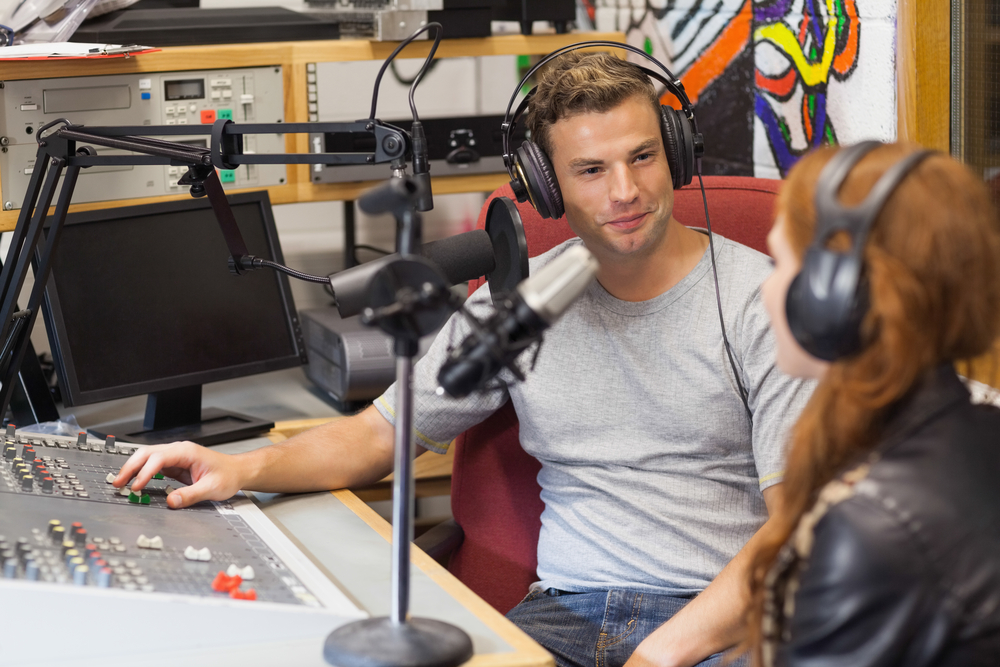 Attractive content radio host interviewing a guest in studio at college