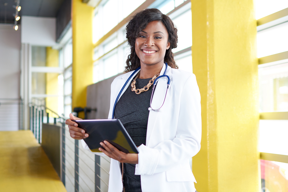 Portrait of a female doctor holding her patient chart on digital tablet in bright modern hospital-1